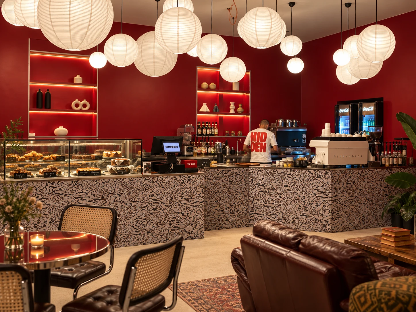 HIDDEN coffee bar with amber pendant lights and pastry display